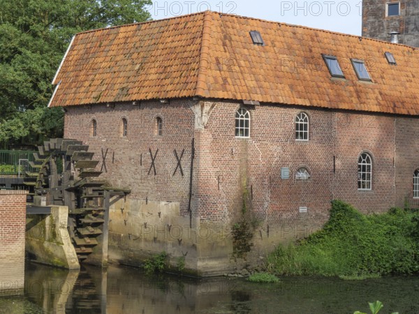 Detailed view of a brick watermill with water wheel and surrounding vegetation, winterswijk,