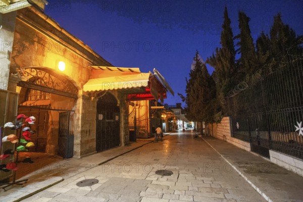Street in Muslim Quarter in Jerusalem old city and stall .People in distance. Blue hour, twilight