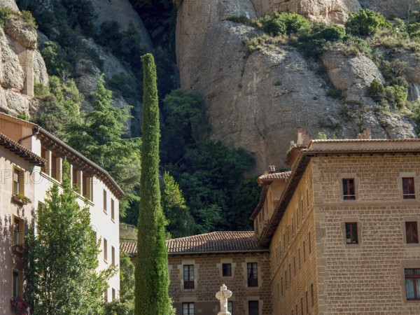 Stone building built against the rocks, surrounded by trees and vegetation, montserrat, spain
