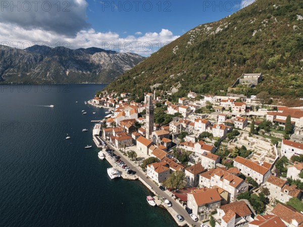 Cars parked on the promenade near the bell tower of the Church of St. Nicholas. Perast, Montenegro.