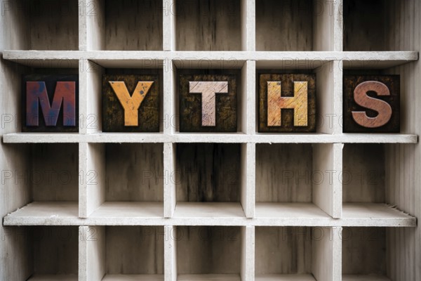 The word MYTHS written in vintage ink stained wooden letterpress type in a partitioned printer's