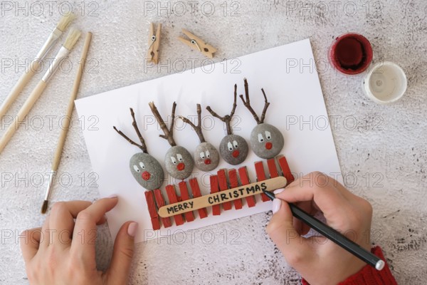 Diy Merry Christmas deer on greeting card postcard made of pebbles, sea stones, clothespins and