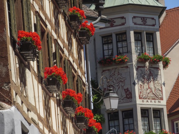 Historic half-timbered house with windows and red flowers under a blue sky, Meersburg, Lake