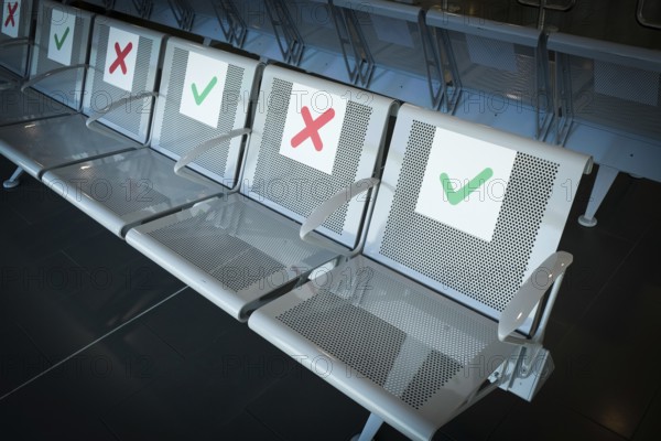 Empty chairs on an airport terminal with signs to keep social distance for the preventions of
