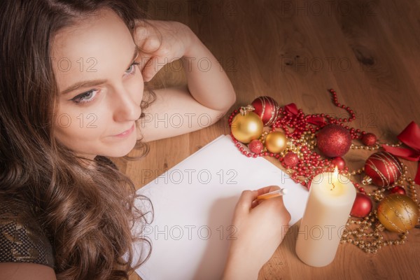 Beautiful smiling woman portrait, thinking about what to write with pencil on blank paper, at