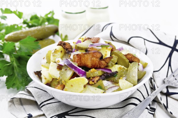 Salad of boiled potatoes, fried bacon, red onions and pickled cucumbers, seasoned with grain