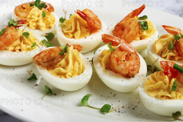 Boiled eggs stuffed with yolk and seasoned with mayonnaise, stuffed eggs with shrimp, on a white