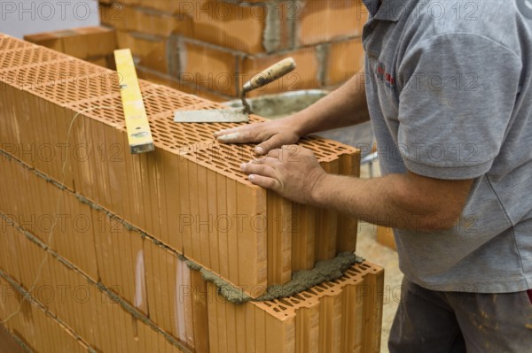 Anonymous construction worker on a building site erecting a brick wall. Brick wall of a solid house