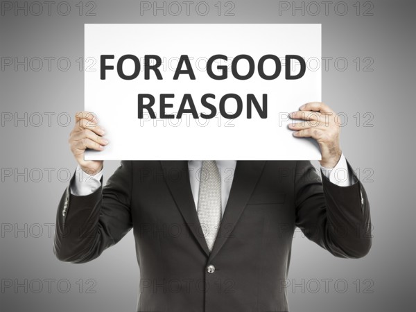 A business man holding a paper in front of his face with the message for a good reason