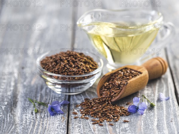 Flax seeds and flax oil. Brown linen seeds, flaxseed oil and blue flax flowers on old gray wooden