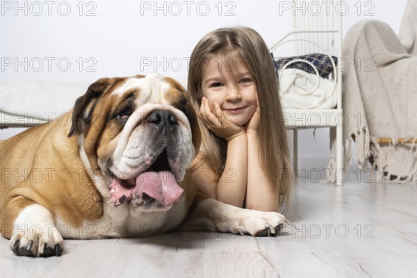 Two dreamy friends, a child and a dog, lie together in the room on the floor next to the bed and