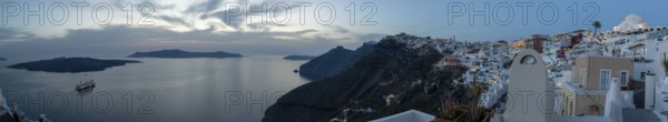 Cruise ship in the archipelago of Santorini, evening mood after sunset, white buildings at the edge
