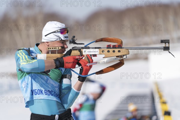 Sportsman biathlete aiming rifle shooting in standing position. Kazakhstan biathlete Kireyev