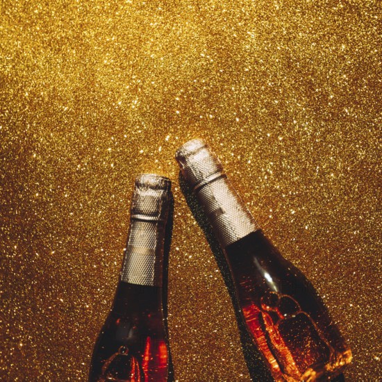 Christmas or New Year composition with bottles of rose champagne on golden shiny background, top