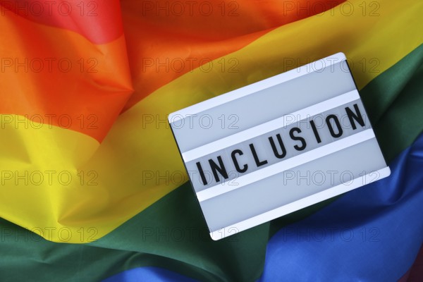 Rainbow flag with lightbox and text INCLUSION. Rainbow lgbtq flag made from silk material. Symbol