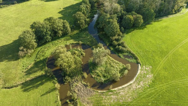 Aerial view of a beautiful green landscape with a small river flowing through. It is in the eastern