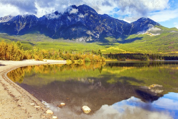 Rocky Mountains of Canada. Smooth water of the lake reflects Pyramid Mountain and lush cumulus