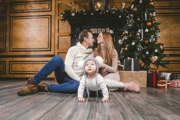 Theme family holiday New Year and Christmas. Young caucasian family mom dad son 1 year sit wooden
