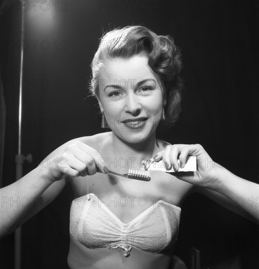 Brushing her teeth in the 1950s. A woman is pressing toothpaste onto her toothbrush. Sweden 1952.