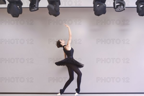 Young ballet dancer black swan practicing before performance in black tutu, classical dance studio,