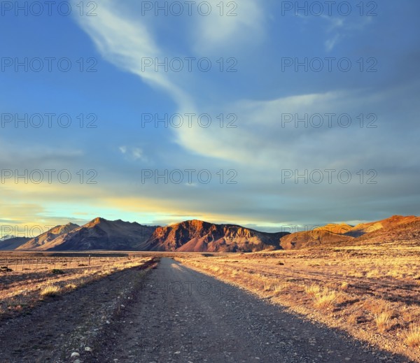 Argentine Patagonia. The gravel road between the endless pampas. The setting sun illuminates the