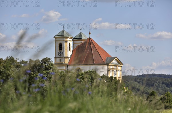 Pilgrimage church Maria Himmelfahrt in Marienberg, blooming meadow and white-blue sky, Burghausen,