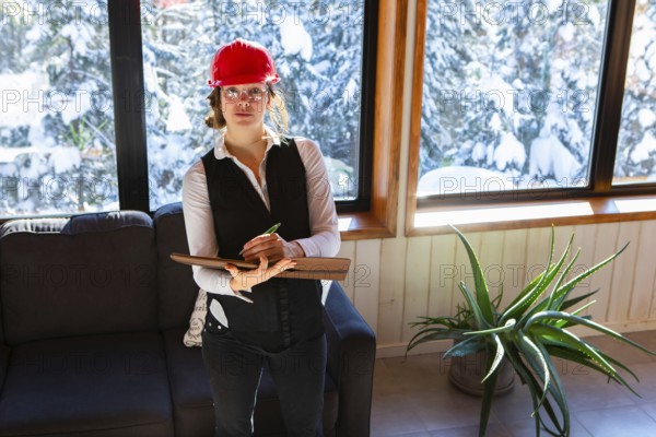 Worker woman at work concept. female home inspector wearing a red hard hat takes professional notes