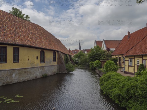 Historic half-timbered houses along a quiet river in dense vegetation, steinfurt, münsterland,