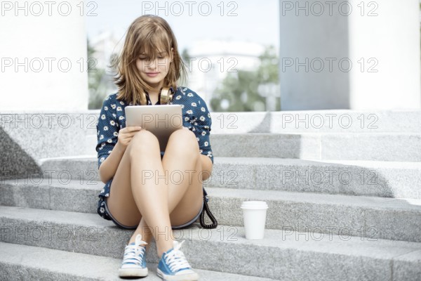 Beautiful young woman with vintage music headphones around her neck and a cup of coffee to go,
