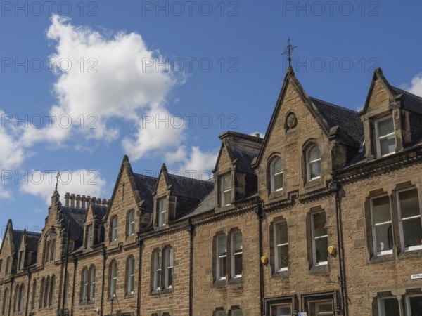 Row of historic buildings with pointed gables and stone facades under a blue sky in a cityscape,