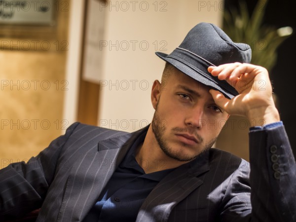 Handsome elegant man in hotel or night club lounge, wearing business suit and fedora hat, looking