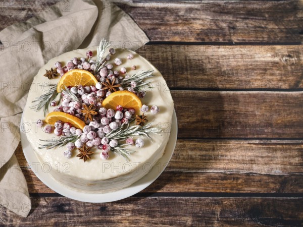Winter homemade cake on wooden background. White cream christmas cake decored rosemary,