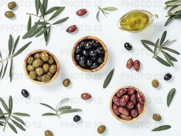 Set of green olives, black olives and red kalmata olives and extra virgin olive oil on white