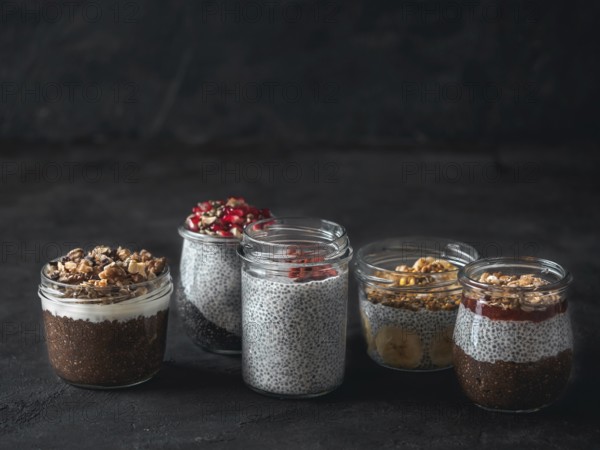 Set of chia pudding in different glass jars on dark table. Assortment of chia puding with different