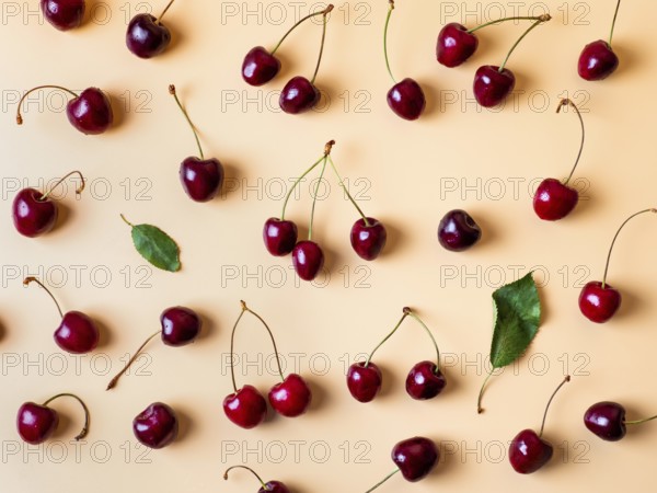 Fresh cherries scattered on yellow background. Creative fresh cherry pattern background with copy