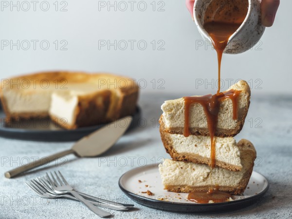 Caramel pouring on stack of three cheesekace pieces. Cheesecake with caramel on gray cement