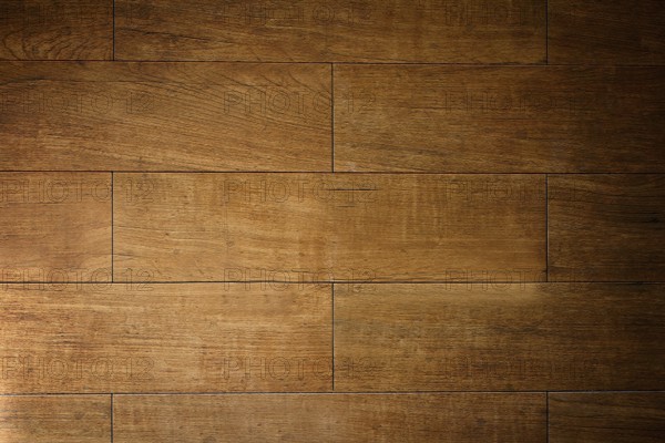 Warm light illuminating textured brown wooden floor tiles, creating a rustic and inviting ambiance