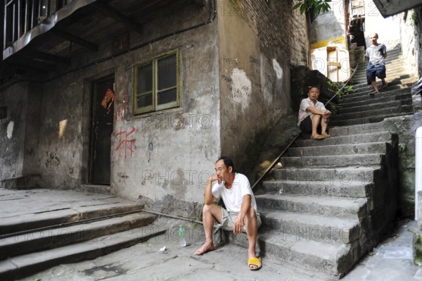 04.08.2012, Chongqing, China, Asia, Men sit on the steps in front of an old house in the old town