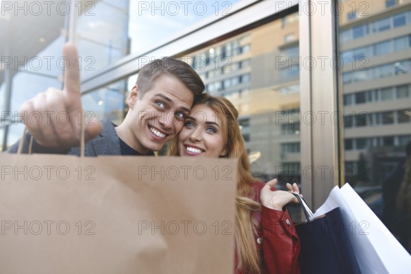 Beautiful couple with shopping bags is talking and smiling while doing shopping in the mall focus