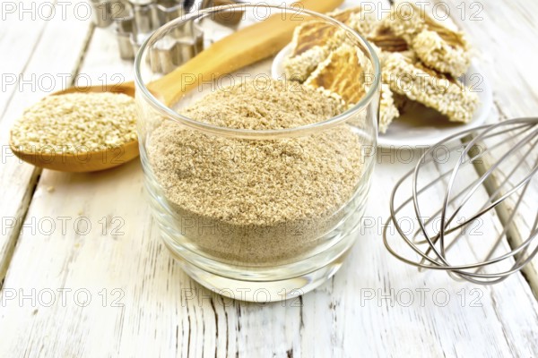 Sesame flour in a glass, a spoon with sesame seeds, cookie cutters and a mixer, biscuit on the