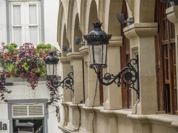 Historic lanterns hanging on the wall of a building with arches and plants in the city, la palma,