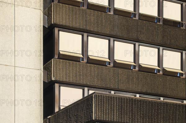 Sunlight illuminating a modernist building facade with ribbed concrete and rows of windows with