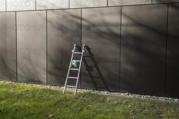 Cleaning crew equipment left on grass lawn in front of modern architecture building facade during