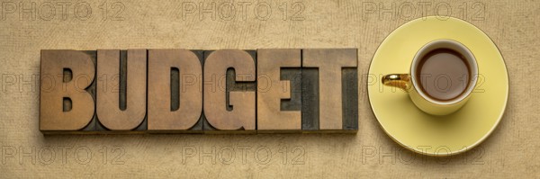 Budget word in vintage letterpress wood type block against textured bark paper with a cup of