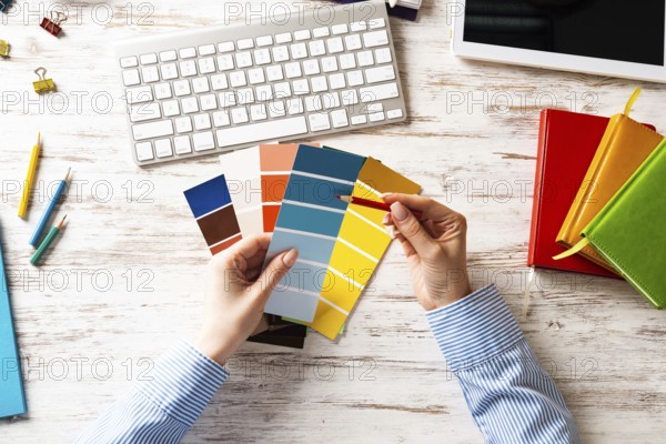 Interior designer choosing colors from swatches at wooden desk. Office workplace with computer