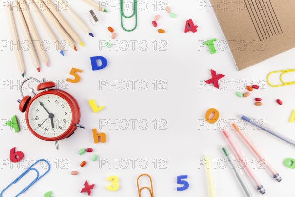 Creative flat lay back to school concept with alarm clock, color school and office supplies on