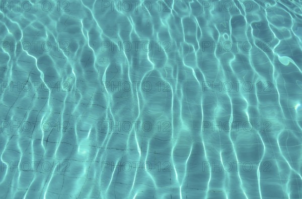 Waves on the light of the pool water. Swimming pool with blue water. Water surface texture. View