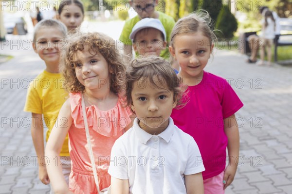 Portrait of happy preschool kids posing closely together outdoors, looking at camera. Lovely boy