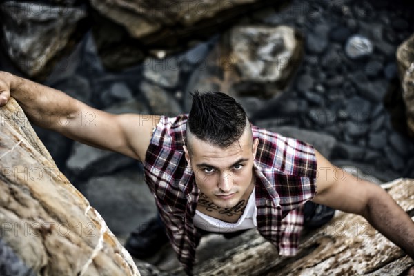 Three Quarter Shot of an Attractive Athletic Young Man Climbing a Rock at the River or by the Sea