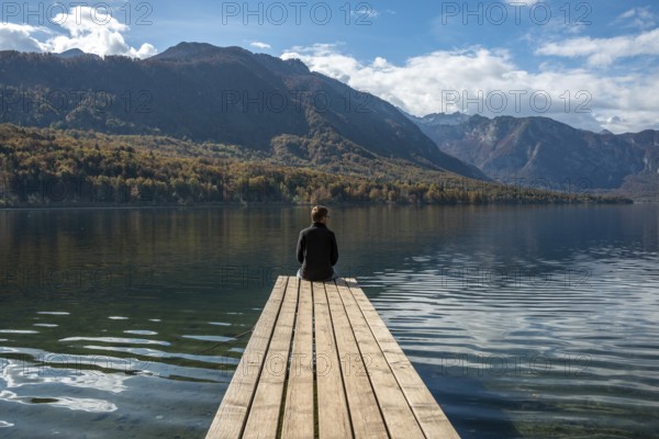 Sitting on a small jetty and enjoying the view on the landscape of lake Bohinj in the Triglav
